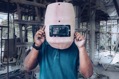 Welder holding welding mask in front of face at construction site