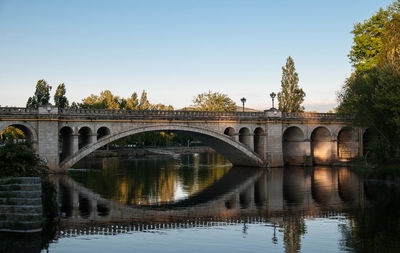 Arch bridge over river against clear sky