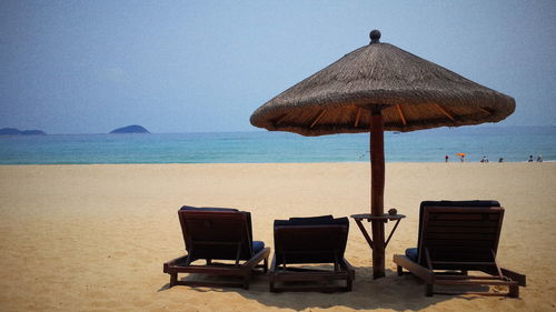 Chairs on beach against clear sky