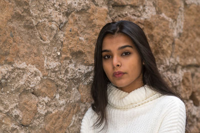 Portrait of a beautiful young woman against wall