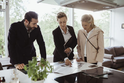 Real estate agent pointing at magazine by male and female partners in new house