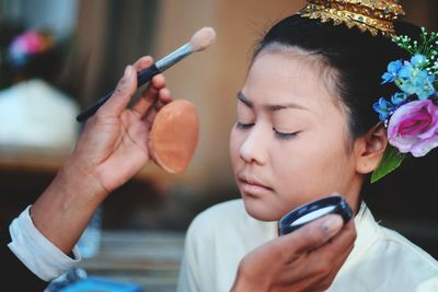 Cropped image of artist applying make-up on young woman