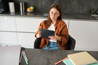 Midsection of woman using digital tablet while standing in office