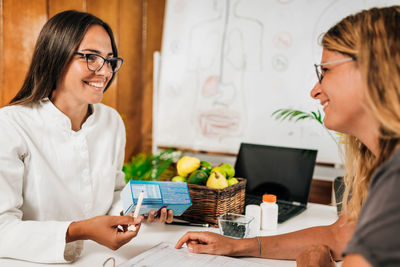 Female nutritionist talking with client about nutritional information on a label of chocolate cookie