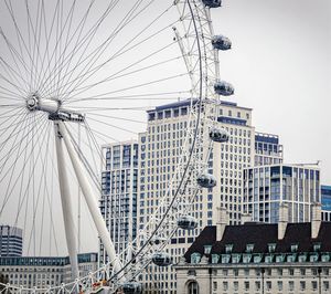 Low angle view of ferris wheel against buildings in city