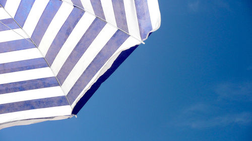 Close-up of cropped umbrella against clear blue sky