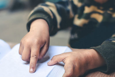Close-up of hand holding book on table