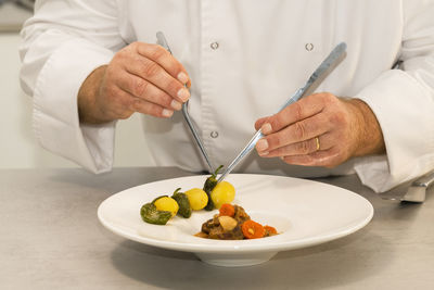 Midsection of man preparing food in plate on table