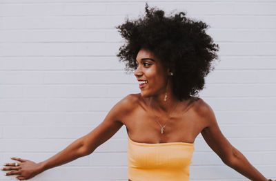 Young woman looking away while standing against wall