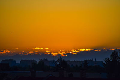 Silhouette trees and buildings against sky during sunset