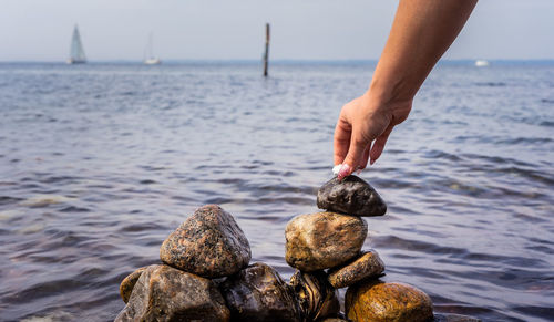 Cropped hand of man stacking stones at beach