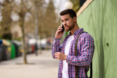 Young man using mobile phone on footpath