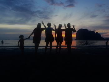 Silhouette people standing on beach against sky during sunset