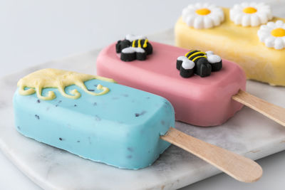 Homemade sweet cakesicles decorated for spring, laying on a marble slab.