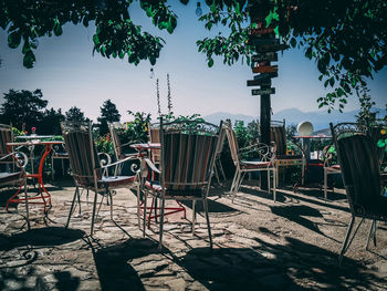 Empty chairs and table in yard against sky