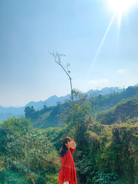 Woman standing by plants against sky