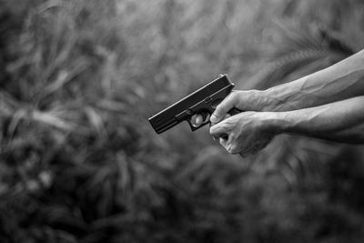 Cropped hands of man holding gun