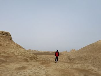 Rear view of man walking on land against sky