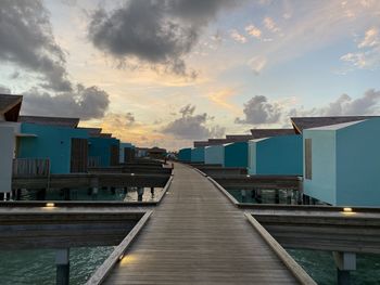 Pier amidst buildings against sky at sunset
