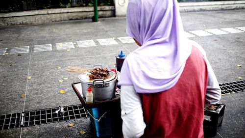 Midsection of woman holding ice cream on footpath
