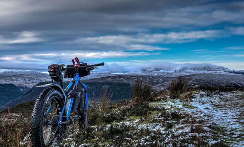 Blue bicycle on mountains against cloudy sky at dusk