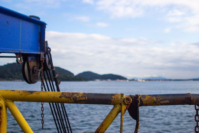 Close-up of rusty metal by sea against sky