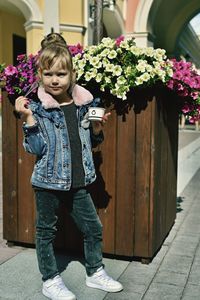 Full length of girl standing by flowering plants