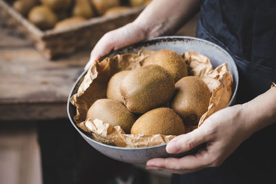 Midsection of person holding kiwis