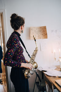 Side view of woman playing saxophone while practicing at studio