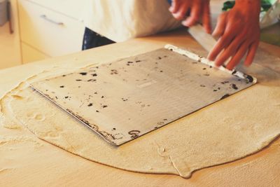 Cropped image of man preparing pizza dough on table