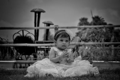 Cute girl sitting on grassy field 