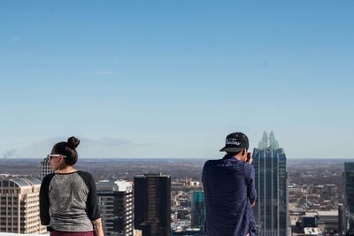 Rear view of man looking at cityscape against sky