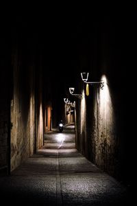 Empty alley amidst buildings in city at night