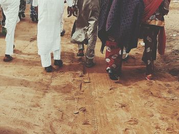 Low section of people walking on dirt road