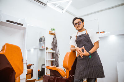 Portrait of young woman using mobile phone while sitting in kitchen