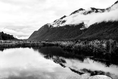 Scenic view of lake by mountains against sky