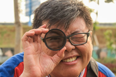 Close-up portrait of smiling man holding eyeglasses