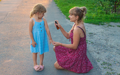 Side view of mother and daughter standing at beach