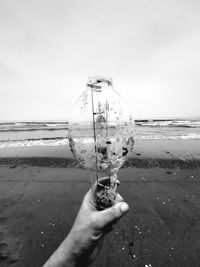 Person holding umbrella on beach against sky