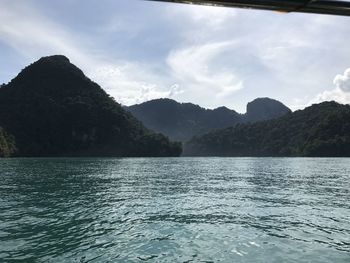 Scenic view of sea by mountain against sky