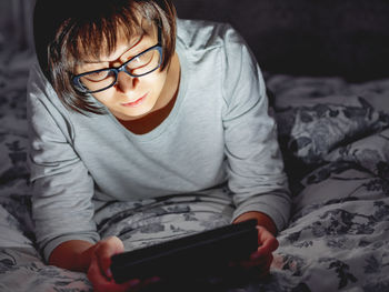 Woman in glasses are lying in bed with tablet in dark room. she is touching screen. night bedtime.