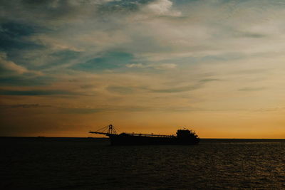 Silhouette ship in sea against sky during sunset