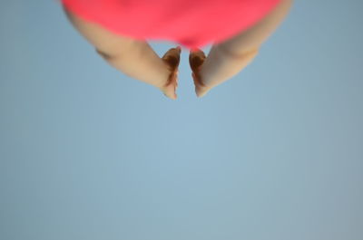 Midsection of woman practicing yoga against clear sky