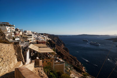 High angle view of townscape by sea against clear blue sky