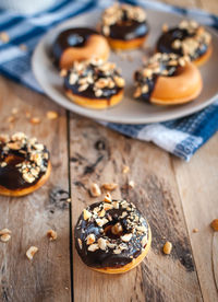 Close-up of chocolate glazed donuts with hazelnuts on wooden background