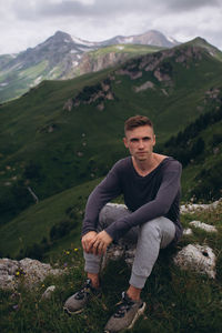 Portrait of young man sitting on mountain