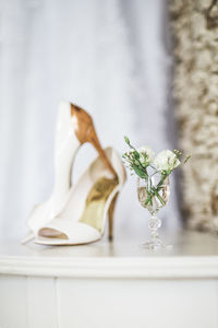 Flowers in glass against high heel sandals on table