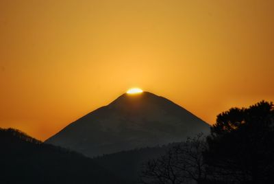 Scenic view of silhouette mountains against orange sky