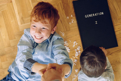 High angle view of smiling boy by sibling playing with alphabets