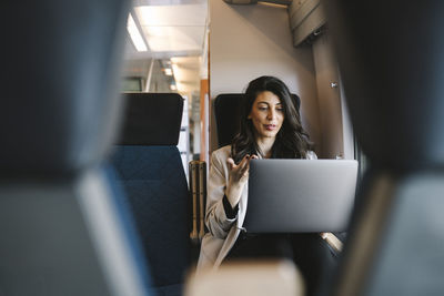 Businesswoman talking on video call through laptop while sitting in train